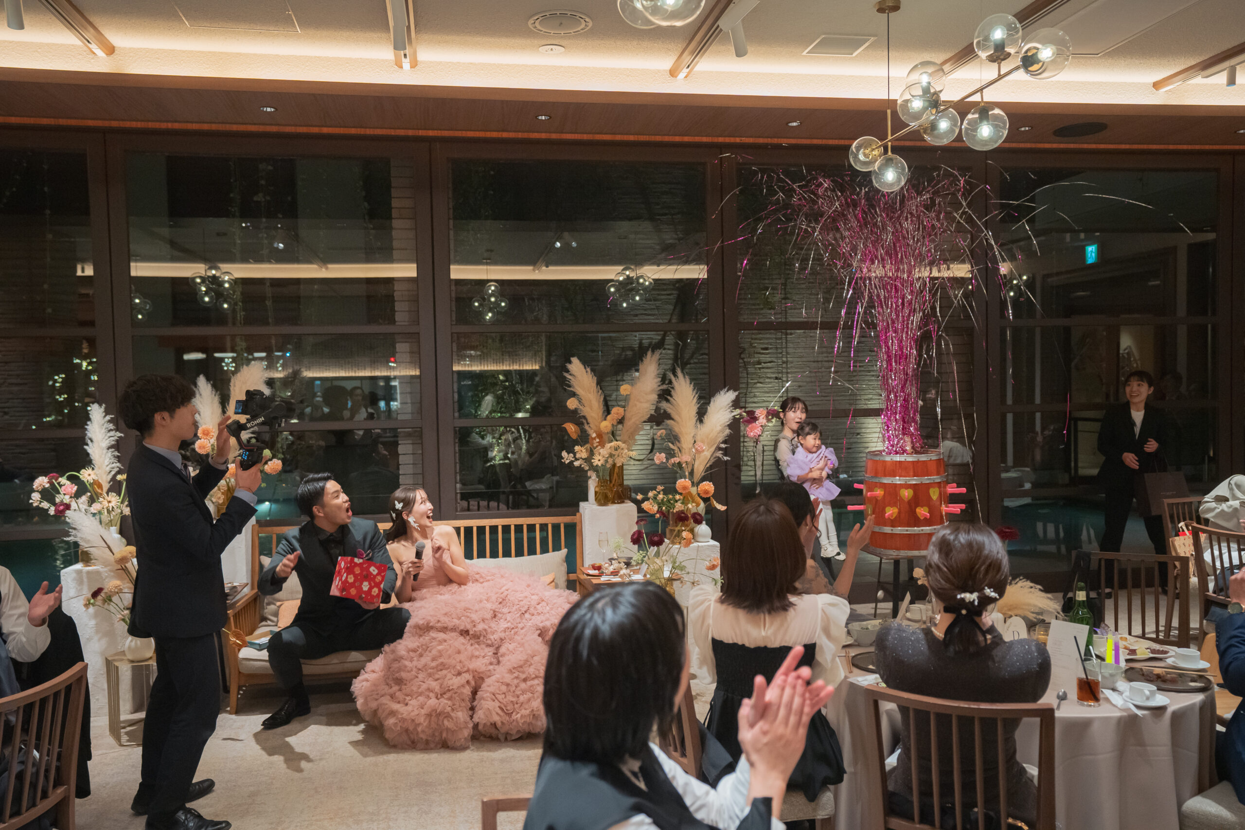 ウィズザスタイルの披露宴会場で、樽のクラッカーの演出に驚く新郎新婦。