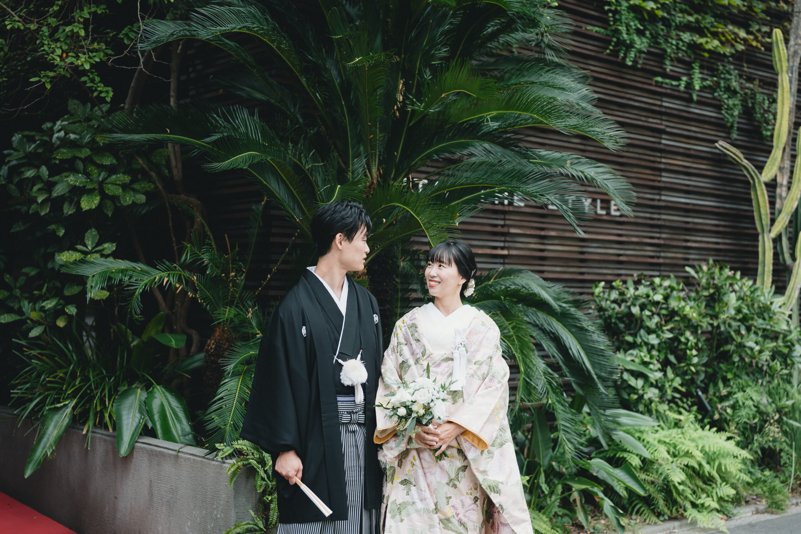 豊かに生い茂る木々の前で笑い合うご新郎様とご新婦様。 