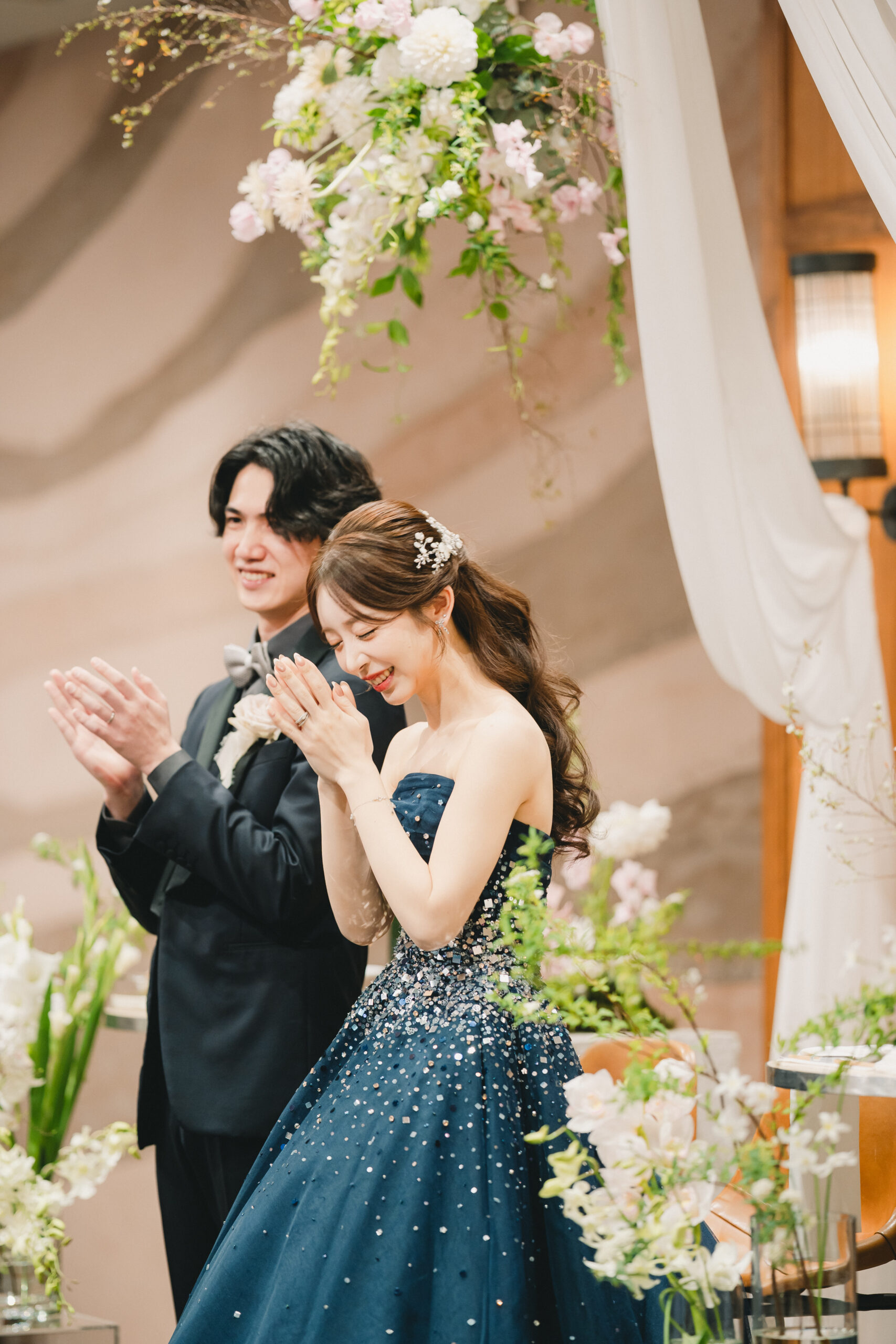 ウィズ ザ スタイルの披露宴会場にて、TREAT ORIGINALのカラードレスを着て微笑んでいるご新婦様とご新郎様