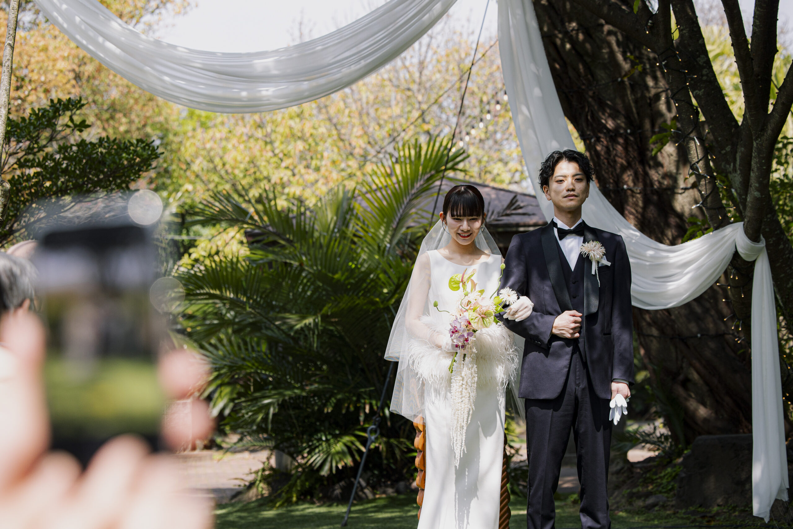 トリート福岡の提携会場のザ ルイガンズ スパ＆リゾートのガーデンで挙式を挙げるご新郎ご新婦様。