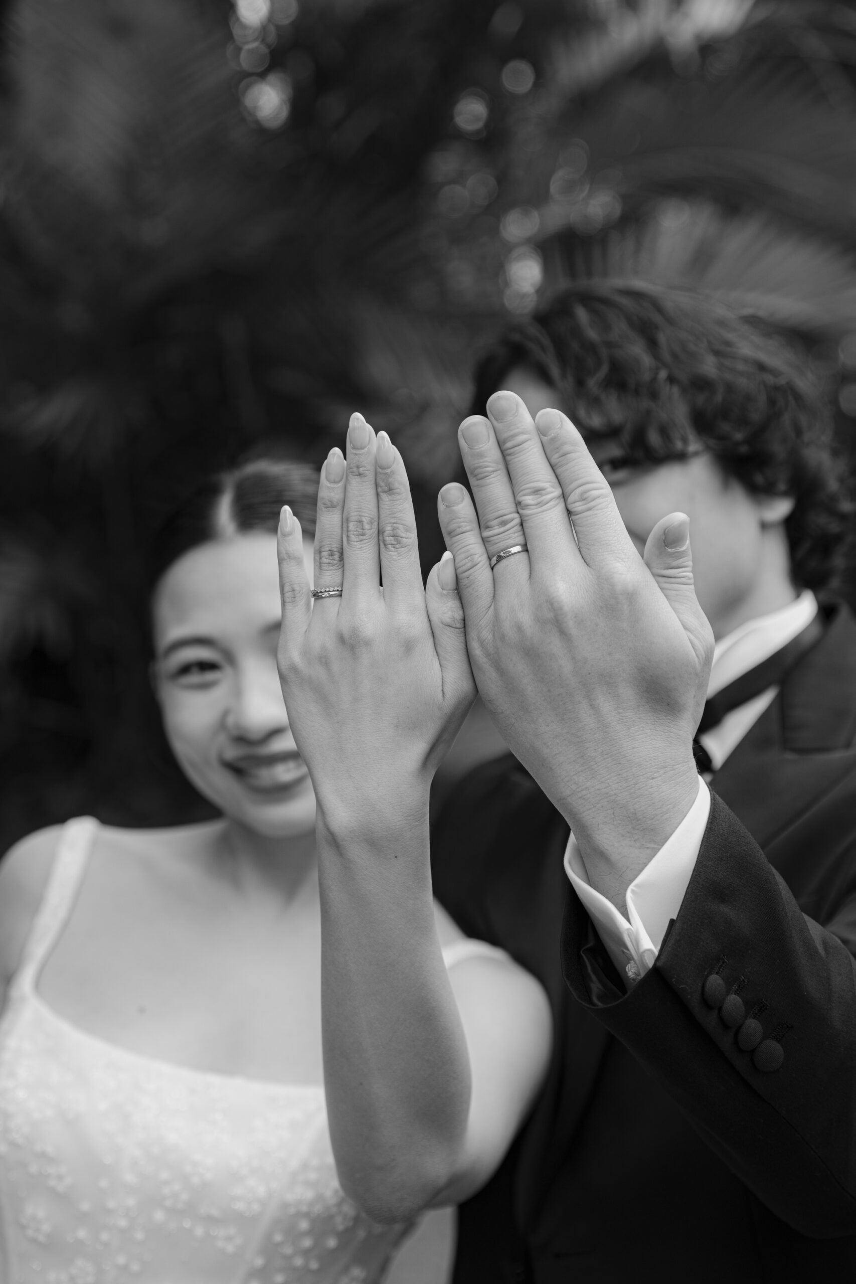 手にはめた結婚指輪をカメラに見せる新郎新婦のモノクロ写真。