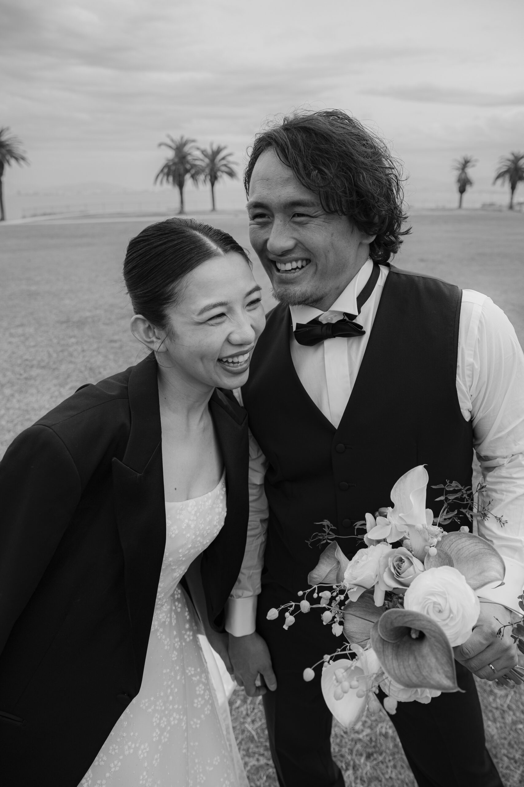 ウェディングドレスにタキシードのジャケットを羽織った新婦様とベスト姿のご新郎様のモノクロ写真。