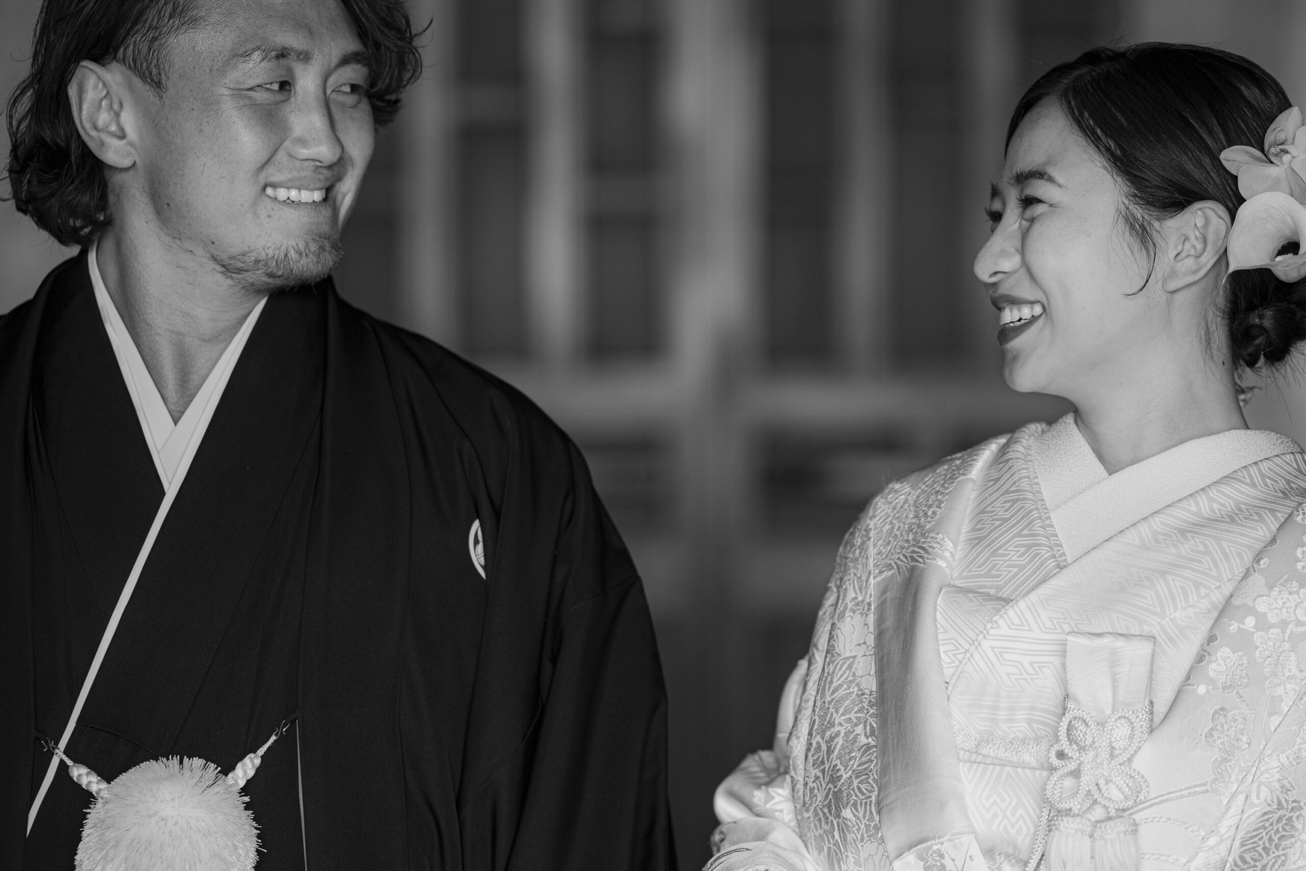 トリート福岡の白無垢と紋付袴姿で顔を見合わせる新郎新婦のモノクロ写真。