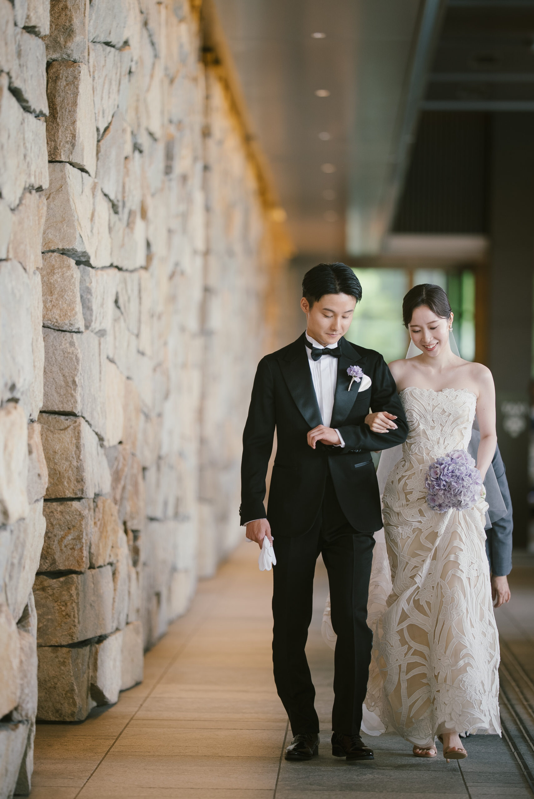 トリートで取り扱いのあるオスカーデラレンタのウェディングドレスを纏うご新婦様と、ブラックタキシードを纏うご新郎様がパレスホテル東京の石畳の車寄せでの情景