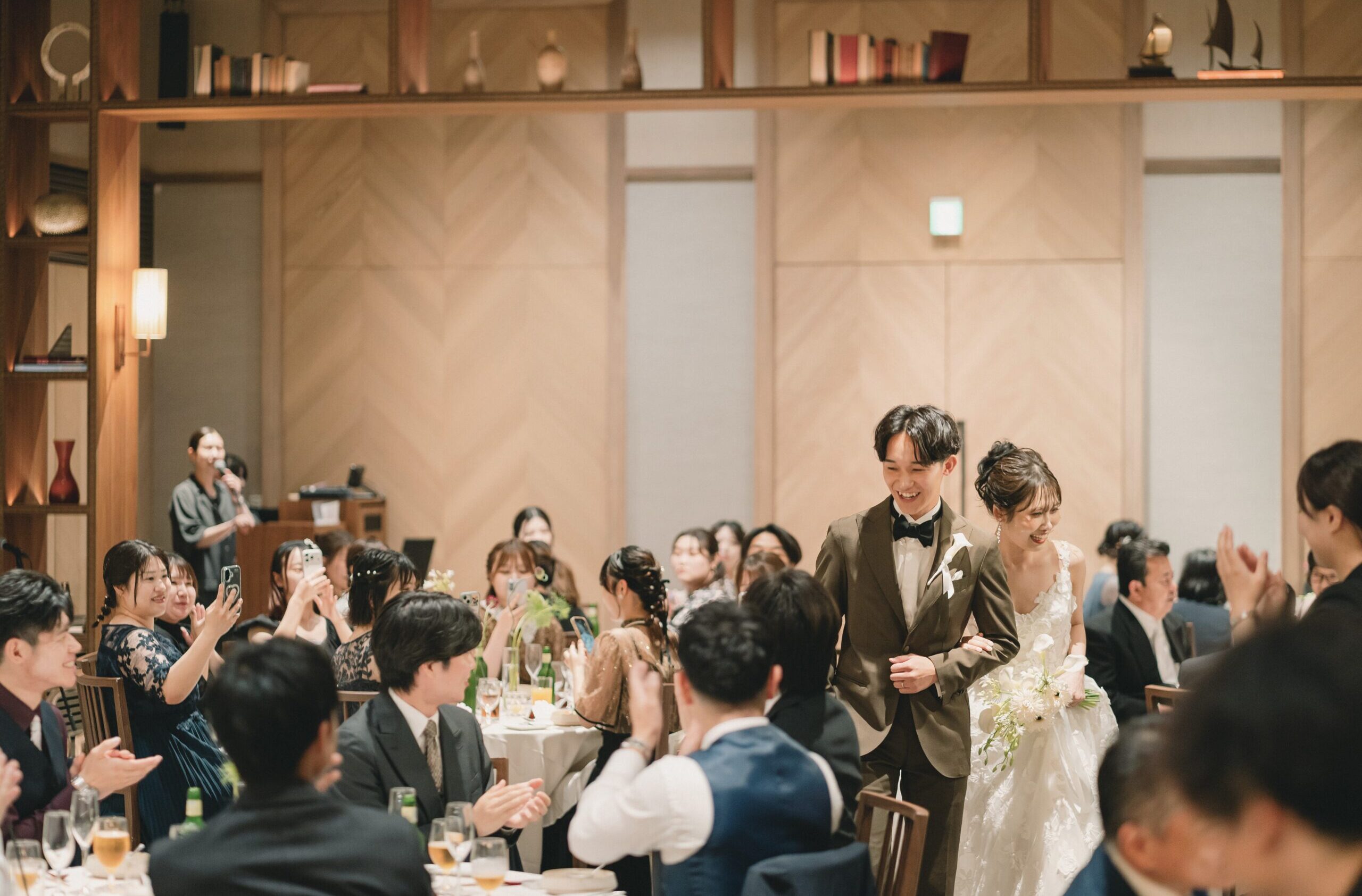 ウィズ ザ スタイル フクオカの披露宴会場にモニーク ルイリエのドレスを着用し入場するご新婦様とご新郎様。