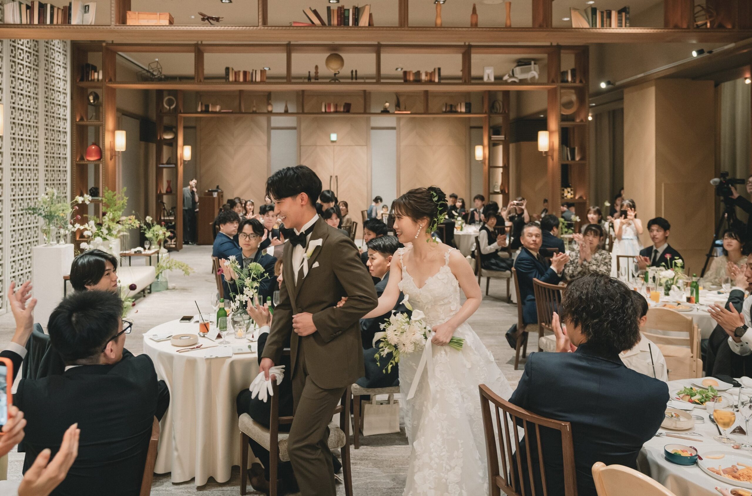 ウィズ ザ スタイル フクオカの披露宴会場にモニーク ルイリエのドレスを着用し入場するご新婦様とご新郎様。