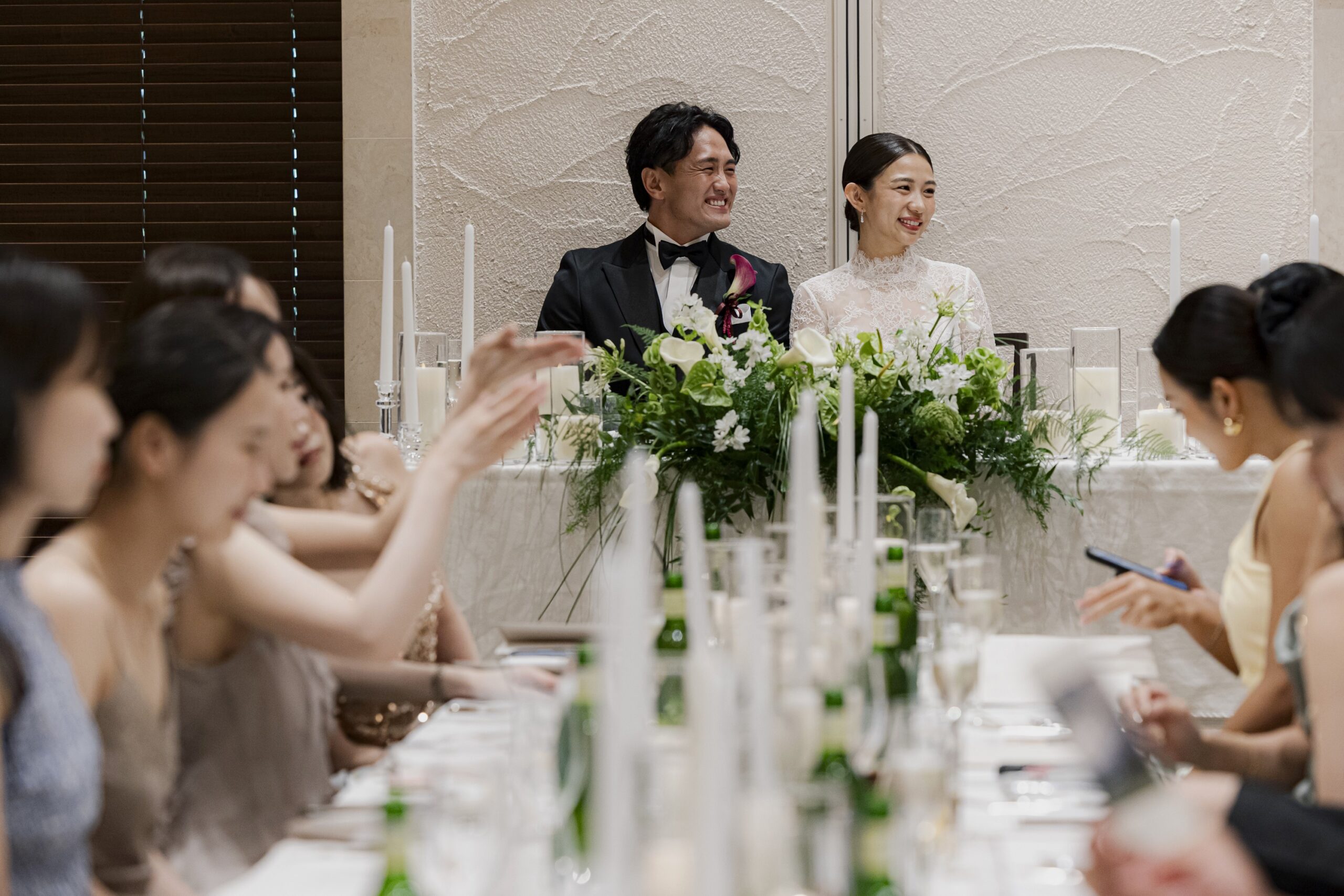 ザ ルイガンズ スパ&リゾートで行う披露宴にて、高砂で微笑んでいるお二人。