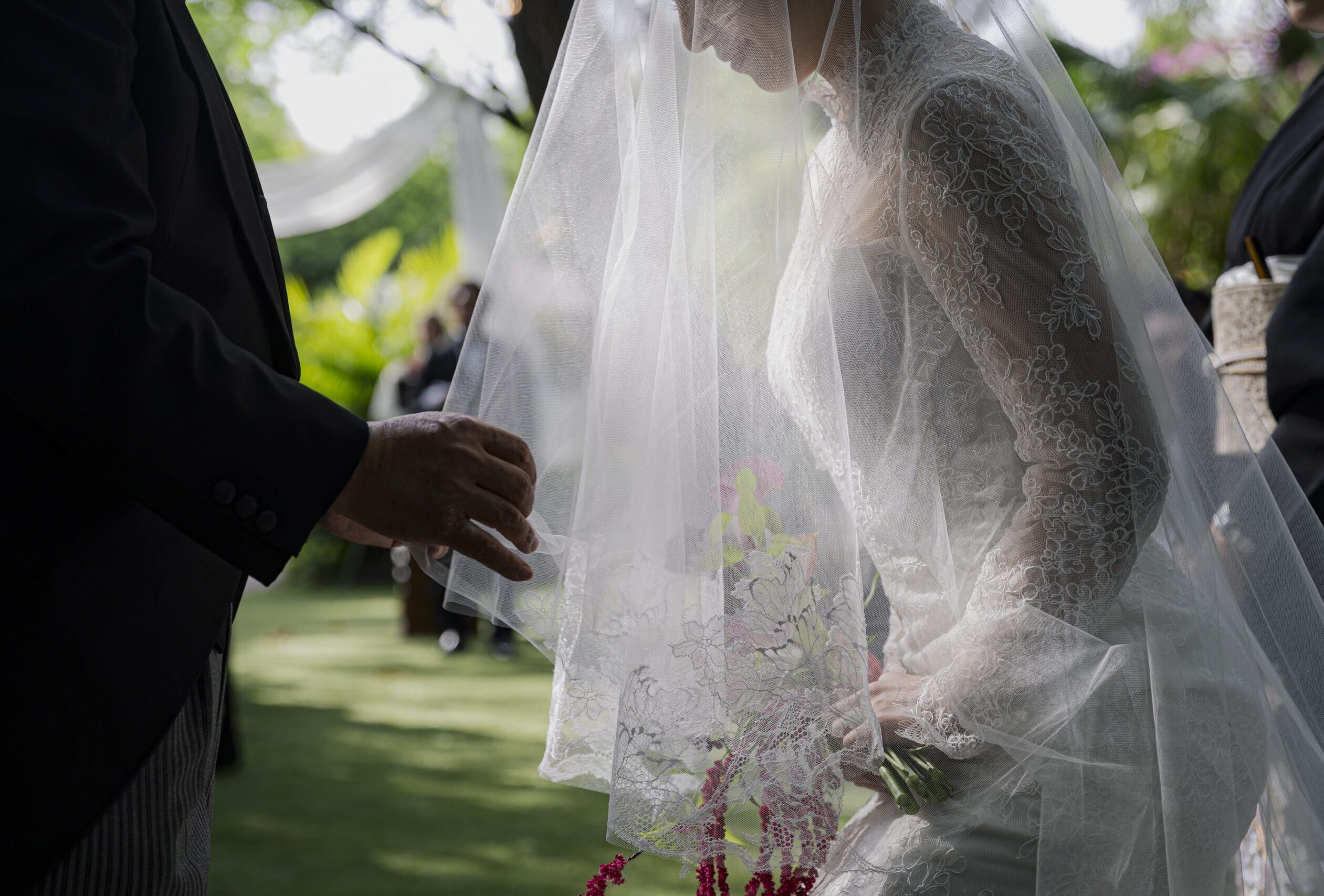 ザ ルイガンズ スパ&リゾートで行うガーデン挙式にて、お父様にベールダウンしていただいているご新婦様。