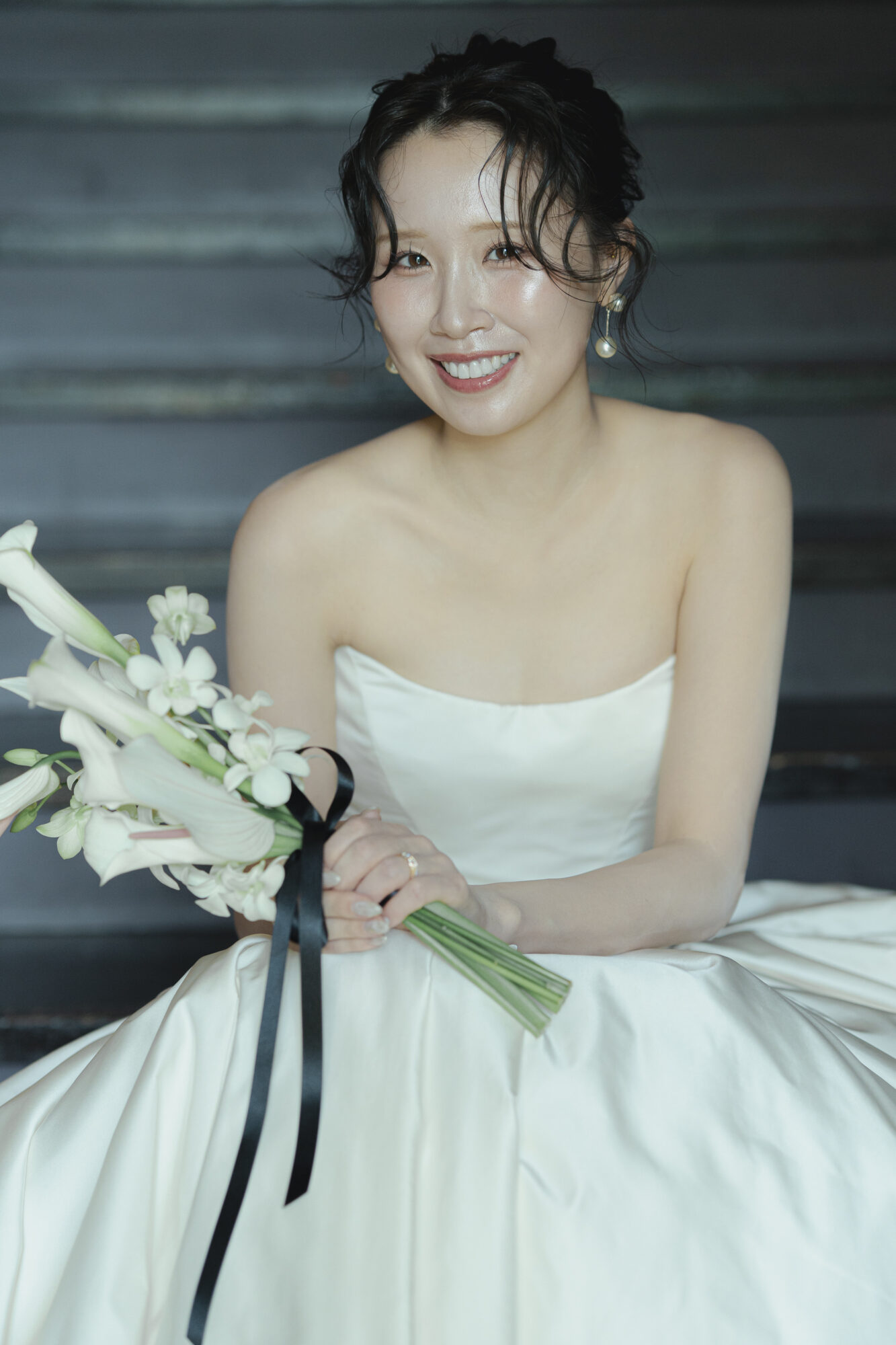 トリート福岡で人気のリーム アクラのウェディングドレスを身に纏い、階段に腰掛けるご新婦様。