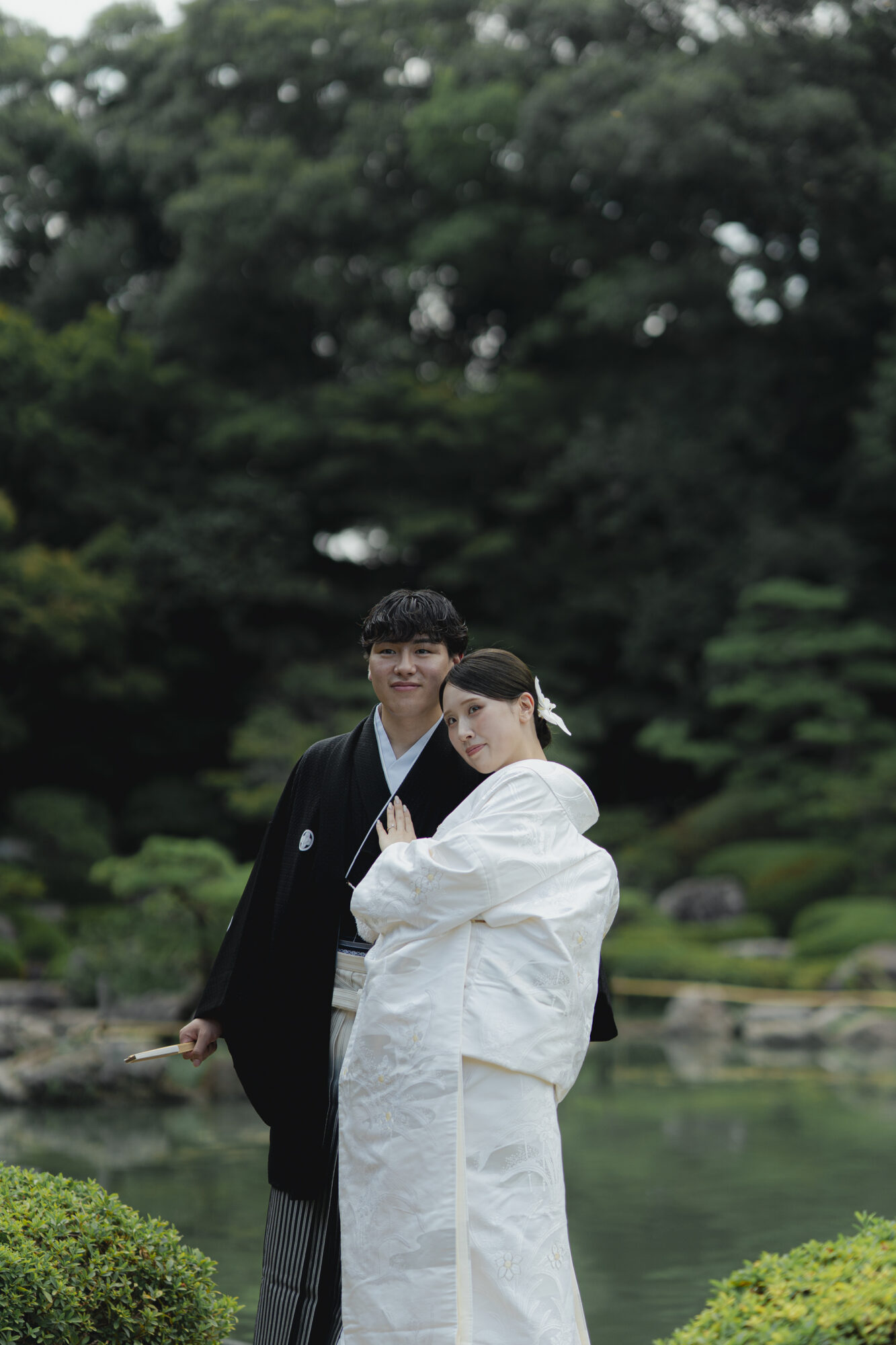 日本庭園で白無垢と紋付袴を着て写真撮影をする、ご新郎ご新婦様。